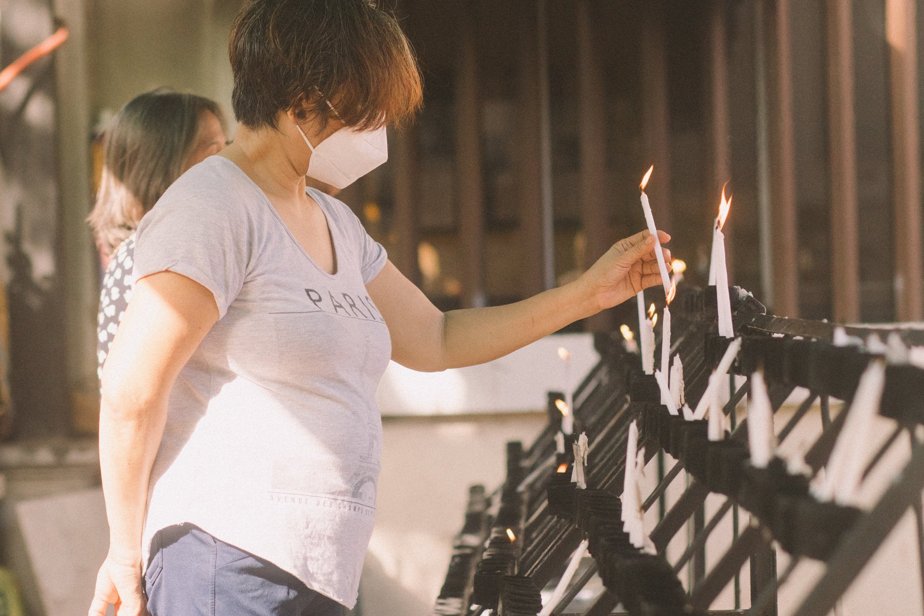 Woman in Face Mask Putting Candle on a Stand